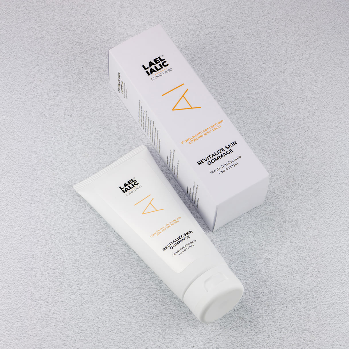 Tubo e confezione distesi del Revitalize Skin Gommage Lael Ialic, scrub rivitalizzante per viso e corpo con acido ialuronico, su sfondo chiaro e testurizzato.